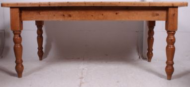 A large Victorian style pine country refectory dining table raised on turned legs with flared top