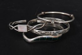 A collection of silver ladies bangles to include a Malachite set bracelet, pierced hoop bangle,