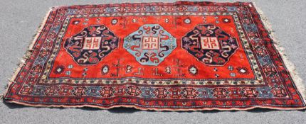 A 20th century Persian rug having red ground, medallions to centre having tassled ends.