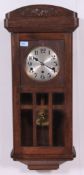 A 1930's Art Deco oak drop dial cased wall clock having a silvered dial with pendulum window.