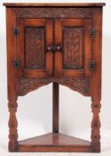 A 20th century Jacobean style oak corner cabinet having glazed door cabinet over shelf beneath.
