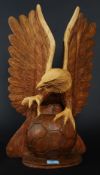A 20th century hand carved Russian ? wooden eagle with ball having raised wings.