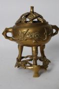 A 20th century Chinese brass incense burner raised over a trivet base complete with frog/grid atop.