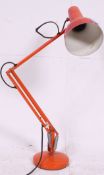 A 20th century Industrial Herbert Terry anglepoise lamp in orange having terraced circular base