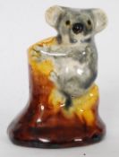 A 20th century Australian ceramic figurine of small proportions - Koala on a tree stump being