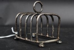 An early 20th century hallmarked silver toast / letter rack of square form standing on bun feet.