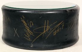 A Nascar Goodyear Eagle race car tyre converted for use as a coffee table having applied glass top.