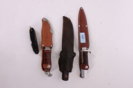 A collection of three hunting knifes in sheathes