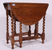 A 1930's oak gate leg Drop leaf barley twist table having legs united by stretchers.