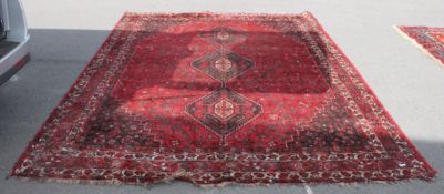 A large 20th century Iranian handwoven Shiraz rug with red ground and stylised medallions bearing