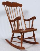 An antique style 20th century Windsor style rocking armchair raised on turned legs with sleigh