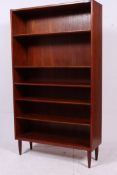 A tall 1970's teak Danish bookcase raised on tapered supports having an upright body with