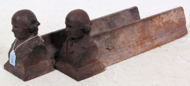 A pair of Victorian cast iron fire dogs, decorated with figural busts to the ends,