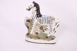 A 19th century Staffordshire flatback figurine of a Zebra raised over a plinth base ( unsigned to