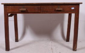 A mid 20th century Air Ministry style solid oak school desk raised on squared legs with twin frieze