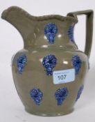 A 19th century green glazed jug with blue glaze fleur de lys / urn embellished sides.