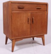 A 1950's Ernest Gomme for G-Plan light oak secretaire chest of drawers being raised on tapered