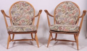 A good pair of retro beech and elm Windsor pattern Ercol armchairs raised on turned legs with