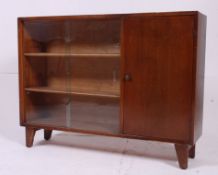 A mid 20th century dark oak sliding glass window bookcase cabinet being raised on squared supports.