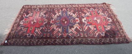 A 20th century handwoven rug of Iranian origin having red ground with geometric borders and