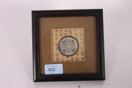 A bronze Chinese oriental good luck amulet / token, framed on inscribed paper backing.