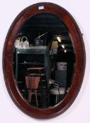 A large 1920's solid oak Jacobean revival bevelled edge wall mirror having hanging hooks to verso