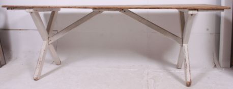 A large country pine trestle refectory dining table having painted cross sectioned legs united by