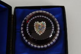 A Perthshire glass circular paperweight of clear of red glass form centred by a Millifiori Heart