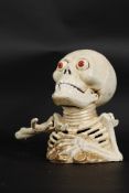 A 20th century cast iron novelty halloween skeleton money box with moving arm and features.