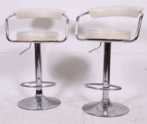 A pair of 20th century contemporary chrome and faux white leather bar stools with padded seats and
