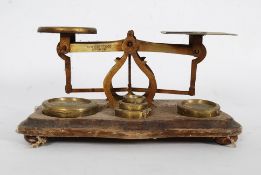 A set of early 20th century brass postal scales complete with the weights being set on a wooden