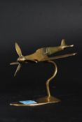 A small table top apprentice piece aircraft possibly a Spitfire raised on a matching brass stand