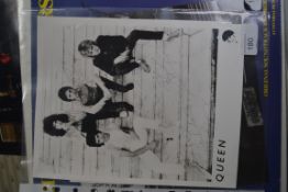 A vintage press photograph of Queen, with signatures.