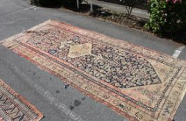 A large early 20th century handwoven rug having geometric patterns to the red ground with tassled