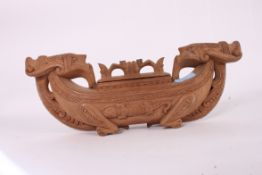 A carved wooden Indonesian feather box in the form of a boat complete with the lid
