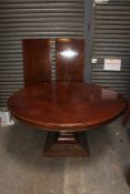A large circular twin leaf extending mahogany dining table raised on a carved oversized base with