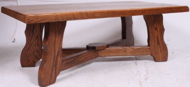 A large solid oak contemporary coffee table raised on squared legs united by stretchers.