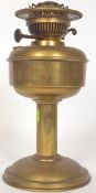 An early 20th century Art Nouveau brass oil lamp having central reservoir with wick and flu atop