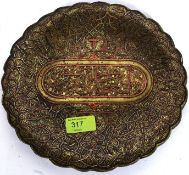 A decorative brass and copper Islamic shallow bowl raised on tripod bun feet having overlaid silver