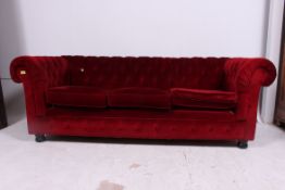 An antique style 20th century Chesterfield sofa raised on bun feet having red velour button backed