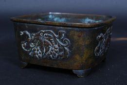 A Chinese square bronze censur / ding cast in relief with grape and vine decoration raised on stub