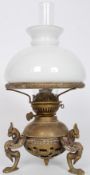 A Victorian brass table oil lamp raised on three winged griffin supports