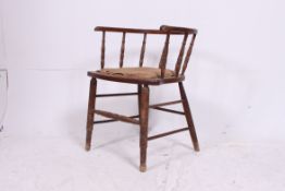An Edwardian oak smokers bow armchair with padded seat ready for upholstery all raised on turned