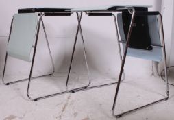 A pair of metamorphic stacking office chairs that each convert to desks to use with chairs,