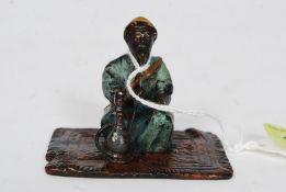 Bergman; An Austrian cold painted bronze figure of a seated man upon a rug,