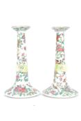 A pair of Chinese Cantonese candlesticks decorated with foliates having single sconces to each