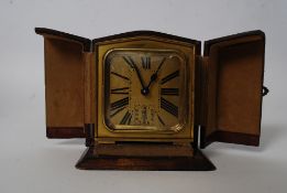 A good early 20th century brass travel clock stamped Brevette SGDG complete with the leather