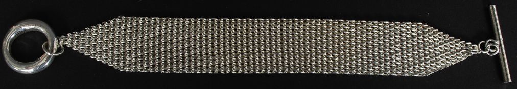 A contemporary silver chain mesh linked braclet with circle and bar clasp,