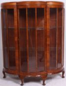 A 1930's walnut Art Deco display cabinet of half moon shape being raised on stub cabriole legs