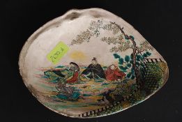 An early Satsuma dish of shell form being handpainted with scenes of scholars under a tree